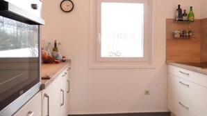 A kitchen with a window, cabinets, and a clock on the wall. - Charming Holiday Home in Liebenscheid by Forest (Liebenscheid)