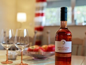A bottle of Spätburgunder Weissbierst wine on a table with glasses and a bowl of fruit. - Cosy Apartment in Neustrassburg (Burbach)