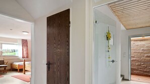 Un intérieur moderne avec une porte en bois, une porte en verre ornée de motifs floraux et un mur en pierre.