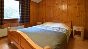 A wooden-paneled bedroom with a bed, a window with curtains, and a nightstand. - Peaceful Holiday Home in Tenneville near Forest (Tenneville)