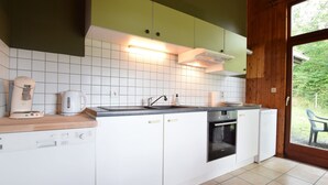 A compact kitchen with white cabinets, a built-in oven, and a coffee maker. - Peaceful Holiday Home in Tenneville near Forest (Tenneville)
