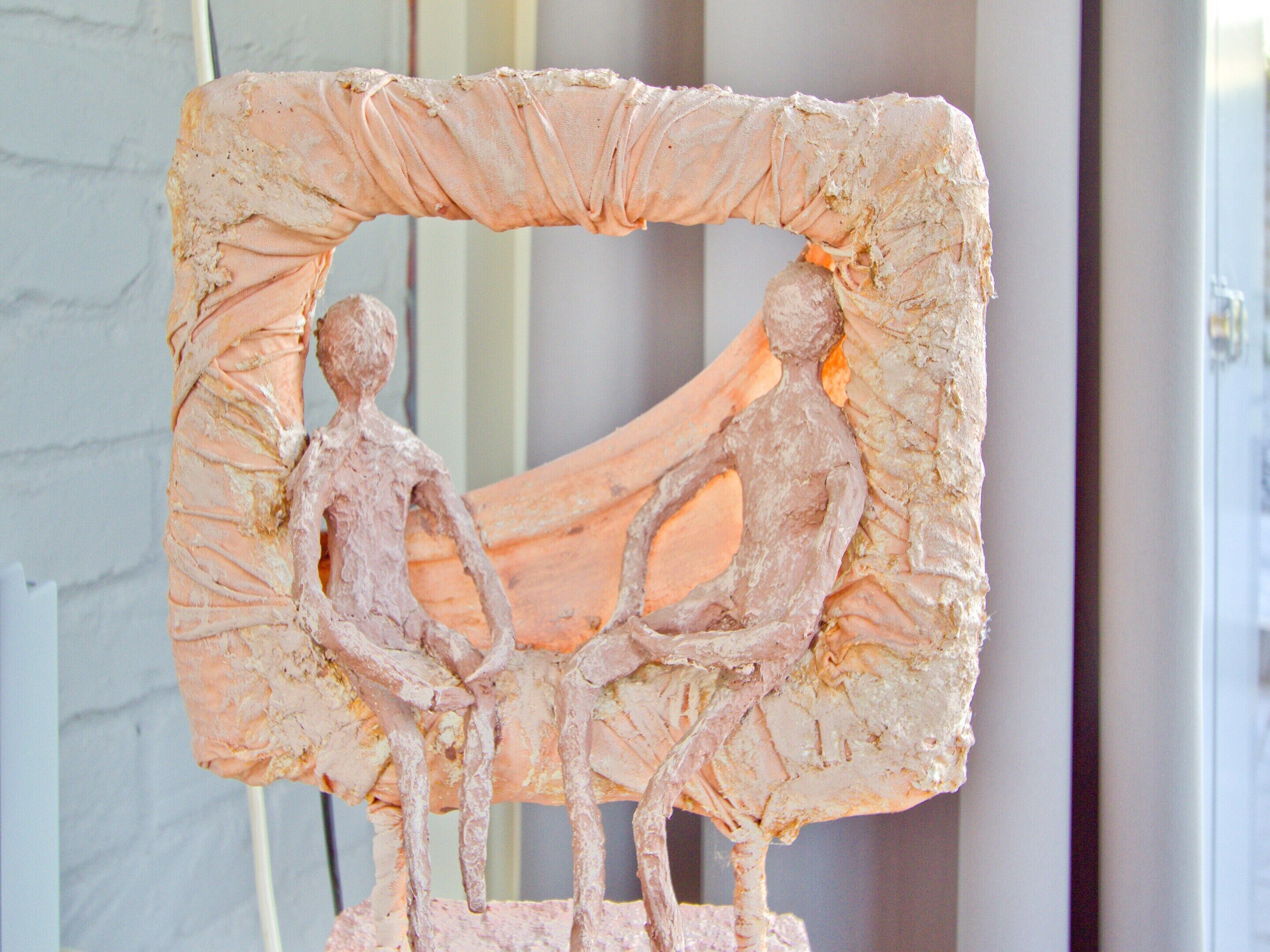 A sculpture of two figures in a rectangular frame.