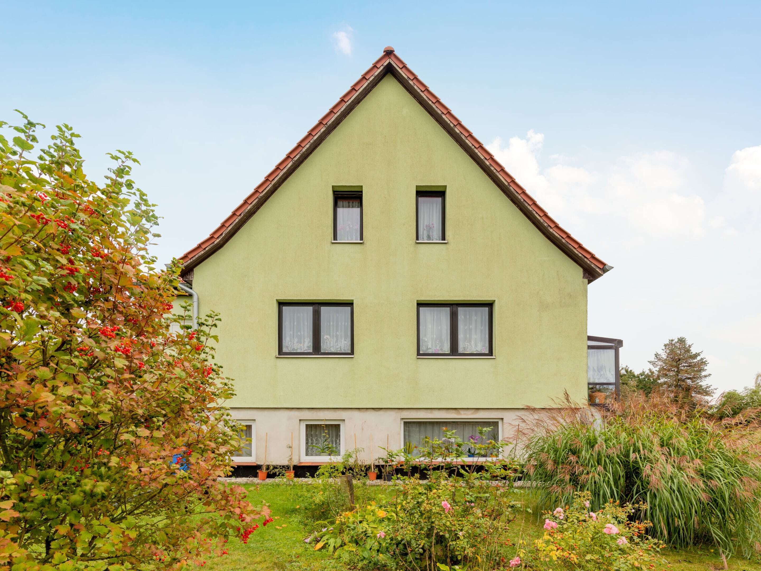 A two-story house with a green facade and a red roof.