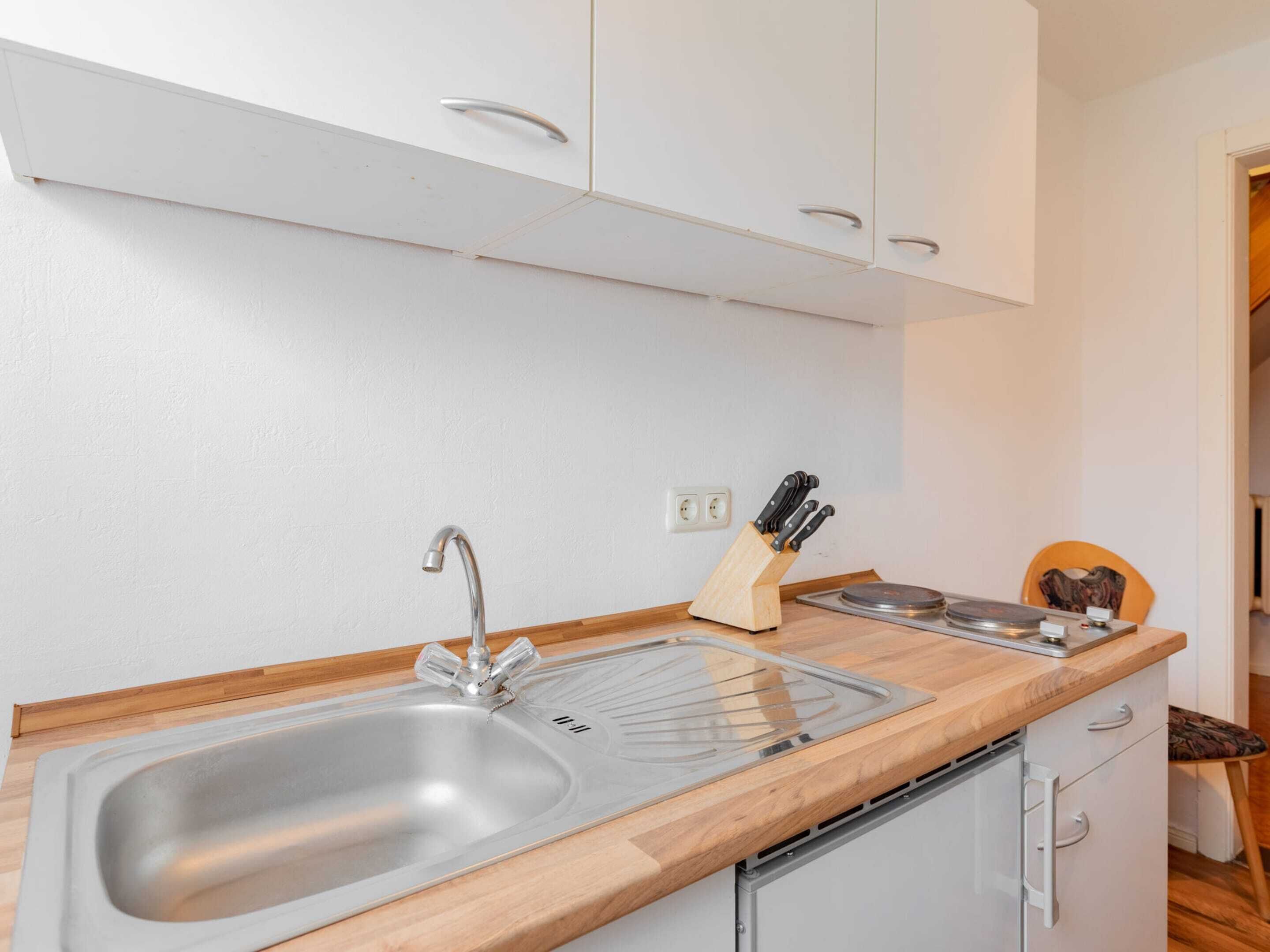 Una cocina con un lavamanos doble, encimera de madera y armarios blancos.