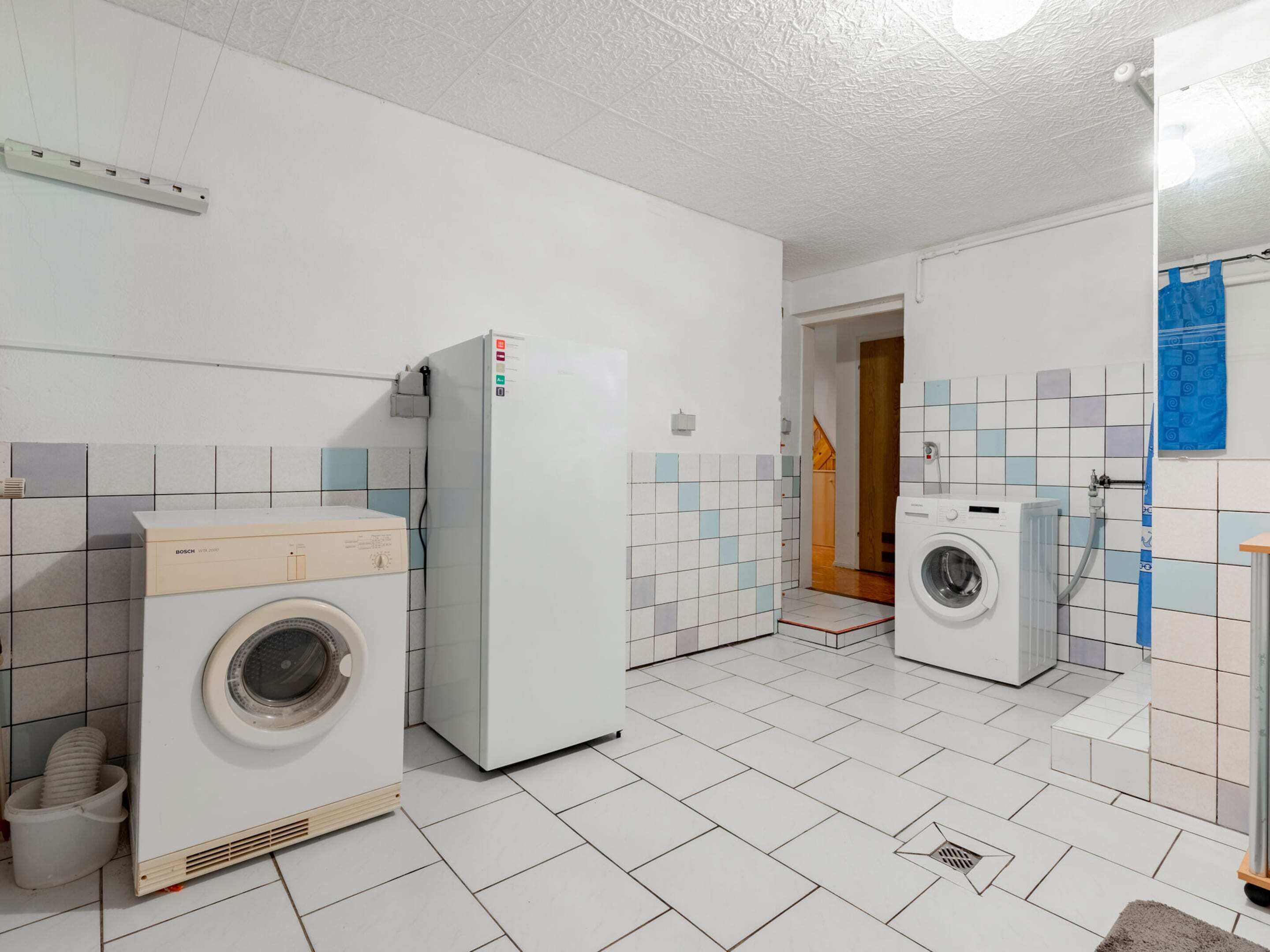Une buanderie équipée de deux machines à laver, d’un sèche-linge et d’un réfrigérateur.