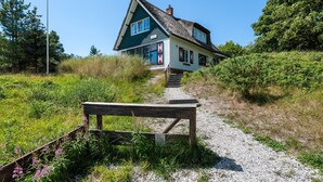 A house with a steeply pitched roof, a chimney, and a gravel path leading to it.