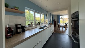 A modern kitchen with a long countertop, built-in oven, and large windows.