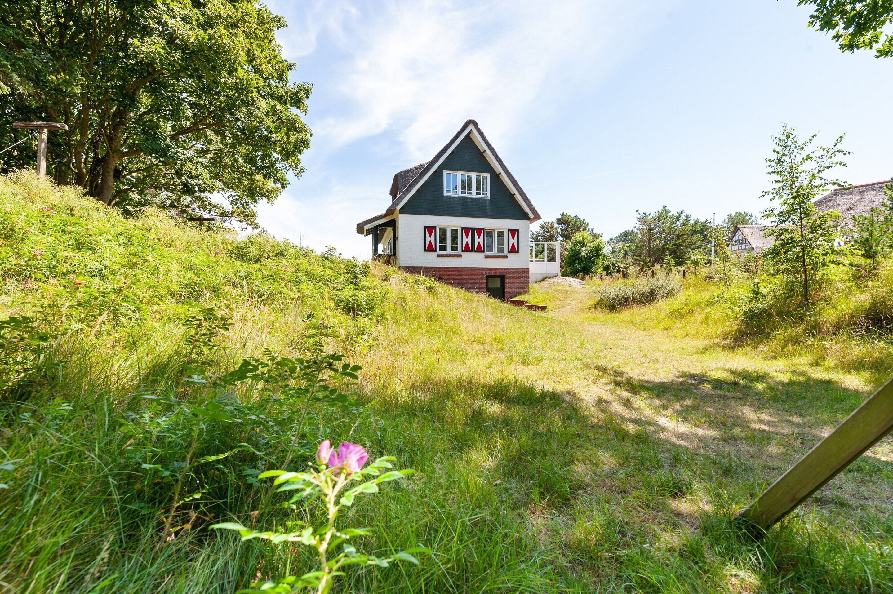 Een huis met een steil dak, een rode deur en een witte raamkozijn.