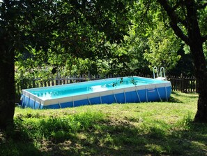 A rectangular above-ground pool with a ladder on one side, surrounded by a wooden fence and trees. - Secluded Chalet With Pool (San Marcello Piteglio)