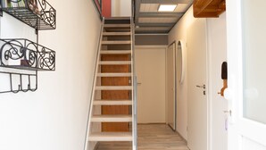 A narrow hallway with a wooden staircase leading to a door. - Ferienhaus in Bestwig mit Privatem Garten (Bestwig)
