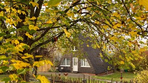 A house with a sloped roof, surrounded by a wooden fence and a garden. - Ferienhaus in Bestwig mit Privatem Garten (Bestwig)