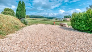 Een grindpad dat naar een gebouw leidt, met een heldere lucht en groen.