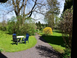 A garden with a gravel path, two blue chairs, and a white table. - Wohnung in Tabarz Thuringen in Waldnahe (Tabarz)