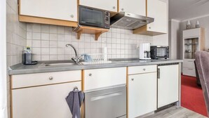 Moderni keittiö, jossa on valkoiset kaapit, Bosch-astianpesukone, mikroaaltouuni ja kahvinkeitin.