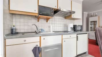 Una cocina moderna con armarios blancos, un lavavajillas Bosch, un microondas y una cafetera.