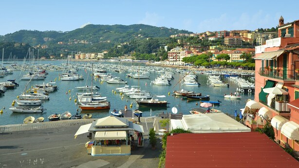 A marina with numerous boats docked, a small kiosk, and buildings with balconies in the background. - Peaceful Countryside Retreat (Sesta Godano)