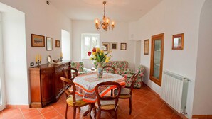 A dining area with a round table, floral-patterned chairs, a wooden cabinet, and a chandelier. - Peaceful Countryside Retreat (Sesta Godano)