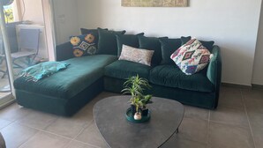 Un salon moderne avec un canapé d’angle, une table basse et une plante en pot.