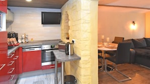 Une cuisine compacte dotée d’appareils électroménagers modernes, un coin repas avec une table et des chaises, et un espace salon confortable avec un canapé.
