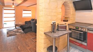 Une cuisine compacte avec une arche en pierre, un grille-pain, une bouilloire et un téléviseur à écran plat fixé au-dessus du four.