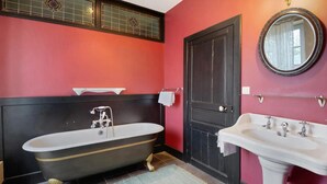 A bathroom with a bathtub, a sink, a door, and a mirror. - Elegant Manor Retreat Normandy (Ponts sur Seulles)
