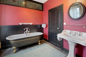 A bathroom with a black bathtub, a white sink, and a red wall. - Elegant Manor Retreat Normandy (Ponts sur Seulles)