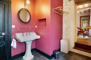 Un baño con lavamanos pedestal blanco, espejo y toallero.