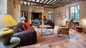 A cozy living room with a fireplace, leather furniture, and a rustic stone wall. - Elegant Manor Retreat Normandy (Ponts sur Seulles)