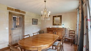 A dining area with a wooden table, chairs, a chandelier, a mirror, and a cabinet. - Elegant Manor Retreat Normandy (Ponts sur Seulles)