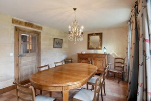 A dining area with a wooden table, chairs, a chandelier, a mirror, and a cabinet. - Elegant Manor Retreat Normandy (Ponts sur Seulles)
