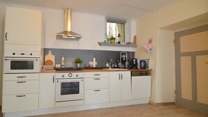 Eine Küche mit weißen Schränken, einem Doppelbackofen, einem Herd, einer Spüle und einem Fenster über der Arbeitsplatte.
