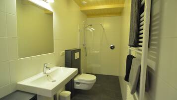 A bathroom with a sink, toilet, shower, and a towel rack.