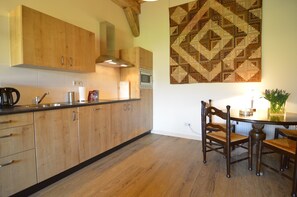 A kitchen with wooden cabinets, a microwave, and a dining area with a table and chairs.