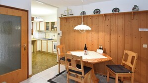 Un comedor con una mesa de madera, sillas, una botella de vino y una copa.