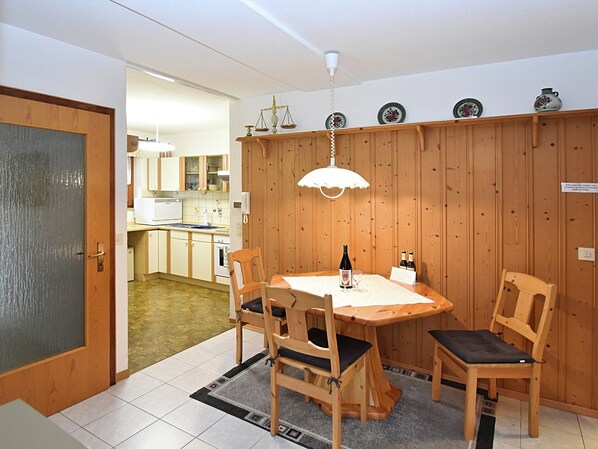 Ein Essbereich mit Holztisch, Stühlen, einer Weinflasche und einem Glas.