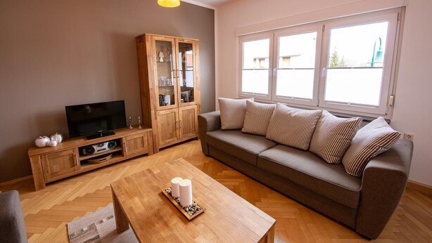 A living room with a sofa, a wooden cabinet, a television, and a coffee table. - Charming Home in Winterstein (Waltershausen)