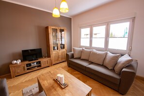 A living room with a sofa, a wooden cabinet, a television, and a coffee table. - Charming Home in Winterstein (Waltershausen)