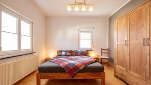 A bedroom with a wooden bed, a large wardrobe, and a window with blinds. - Charming Home in Winterstein (Waltershausen)
