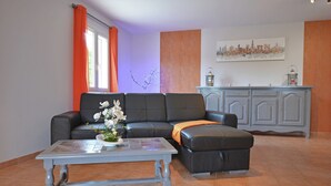 Ein Wohnzimmer mit einer Couch, einem Hocker, einem Couchtisch und einem Schrank.