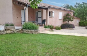 Une maison avec un jardinière en pierre, une porte, une fenêtre et un petit jardin.
