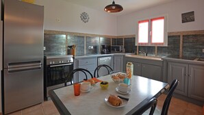 Eine moderne Küche mit Edelstahlgeräten, einem mit Frühstück serviertem Esstisch und einer Pendelleuchte.