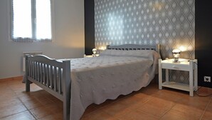 Ein Schlafzimmer mit einem Bett, zwei Nachttischen, einem Fenster und einer Wand mit einem Rautenmuster.
