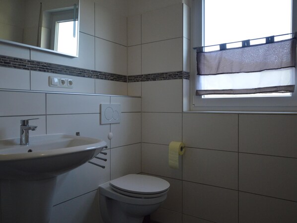 A bathroom with a sink, toilet, and a window with a checkered blind. - Holiday Home in the Eifel With Balcony (Bremm)