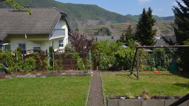 A house with a sloped roof, a front yard with a pathway, and a view of a hilly landscape in the background. - Holiday Home in the Eifel With Balcony (Bremm)