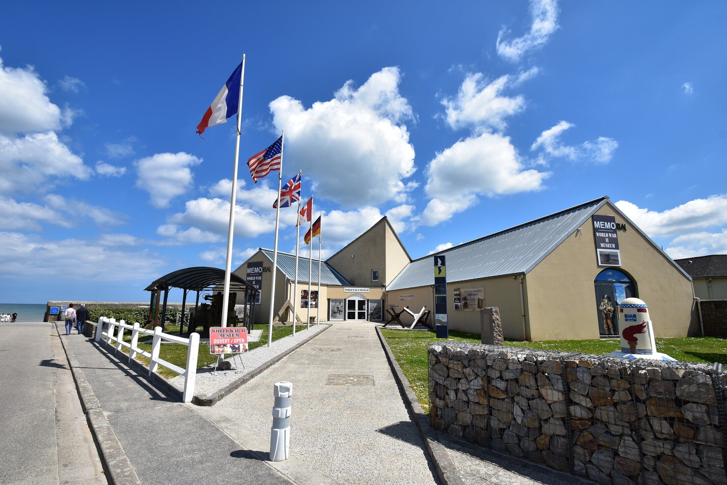 A building with a sign reading 'MEMORIAL WORLD WAR II MUSEUM' and flags on poles.