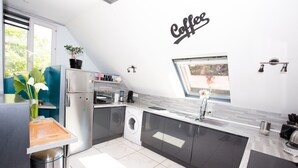 Une cuisine moderne équipée d’un lave-linge, avec un panneau publicitaire pour le café accroché au mur et une fenêtre offrant une belle vue.