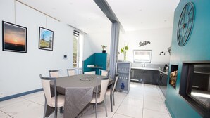 Une cuisine moderne dotée d’un coin café, d’un espace repas avec une table et des chaises, et d’une grande fenêtre.