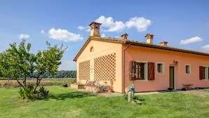 Une maison de plain-pied avec un toit en tuiles, une cheminée en briques et des fenêtres décorées de motifs en treillis.