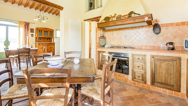 Une cuisine spacieuse avec un dosseret carrelé, des armoires en bois et un coin repas comprenant une table et des chaises.