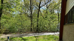 A pathway leading into a wooded area with a building on the right.